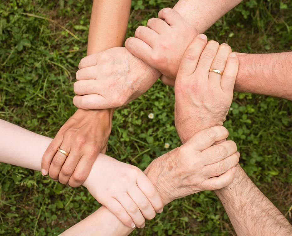 Hands holding wrists in a circle — joining the work together.