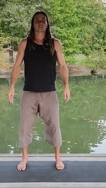 Keith standing barefoot on a mat beside still water